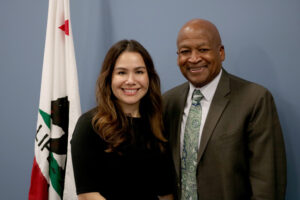 Mayra E Alvarez (left) and Al Rowlett (right) stand next to each other, smiling.