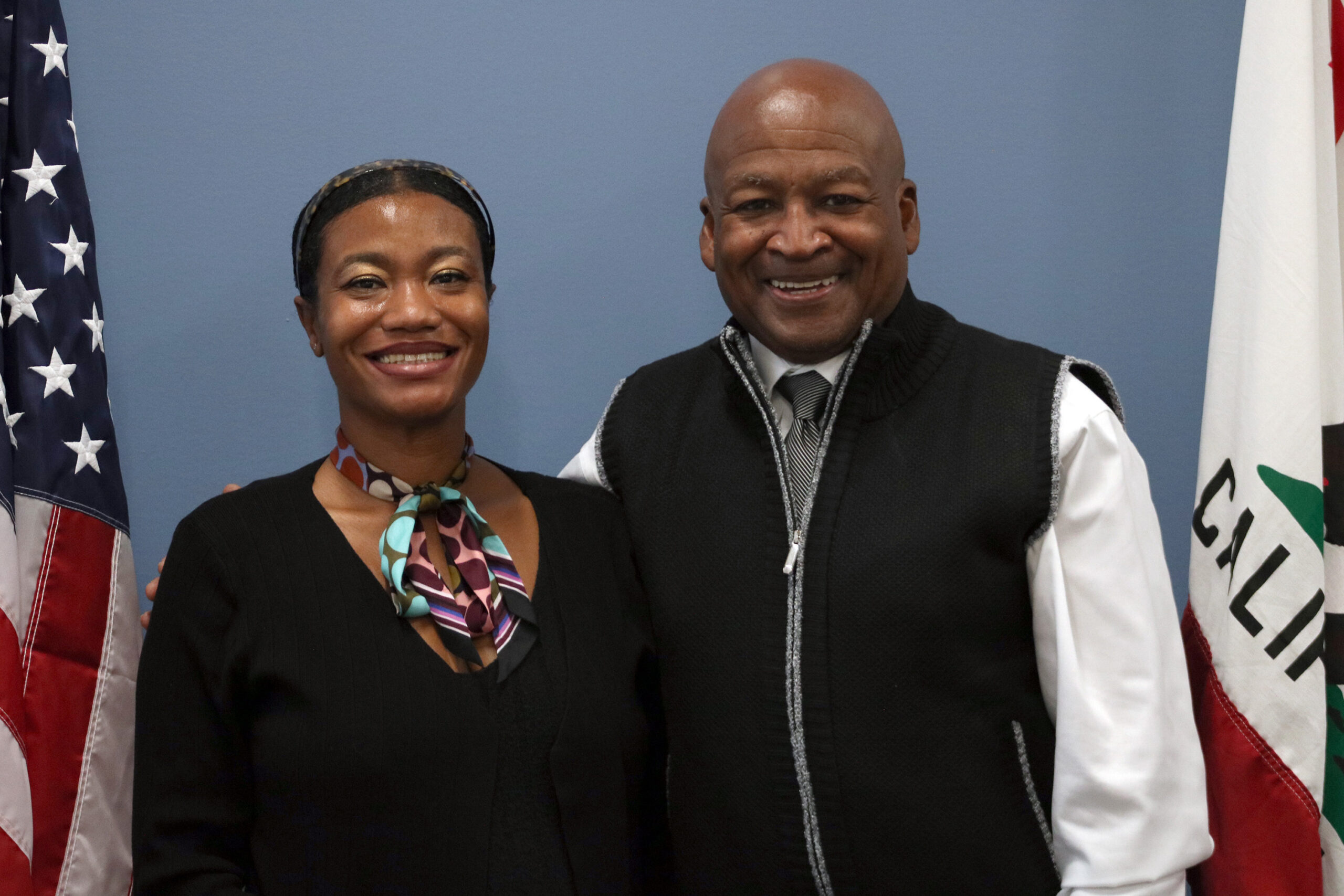 Mayra E Alvarez (left) and Al Rowlett (right) stand next to each other, smiling.