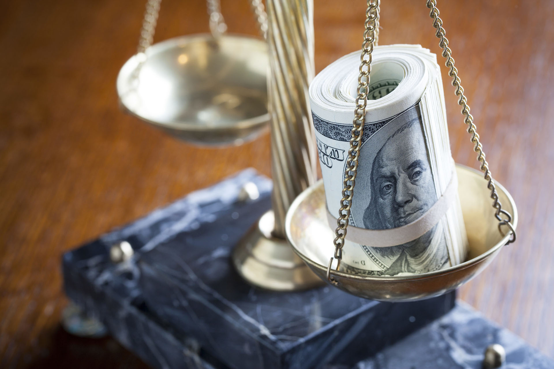A scale with a roll of dollar bills symbolizes balancing expenses